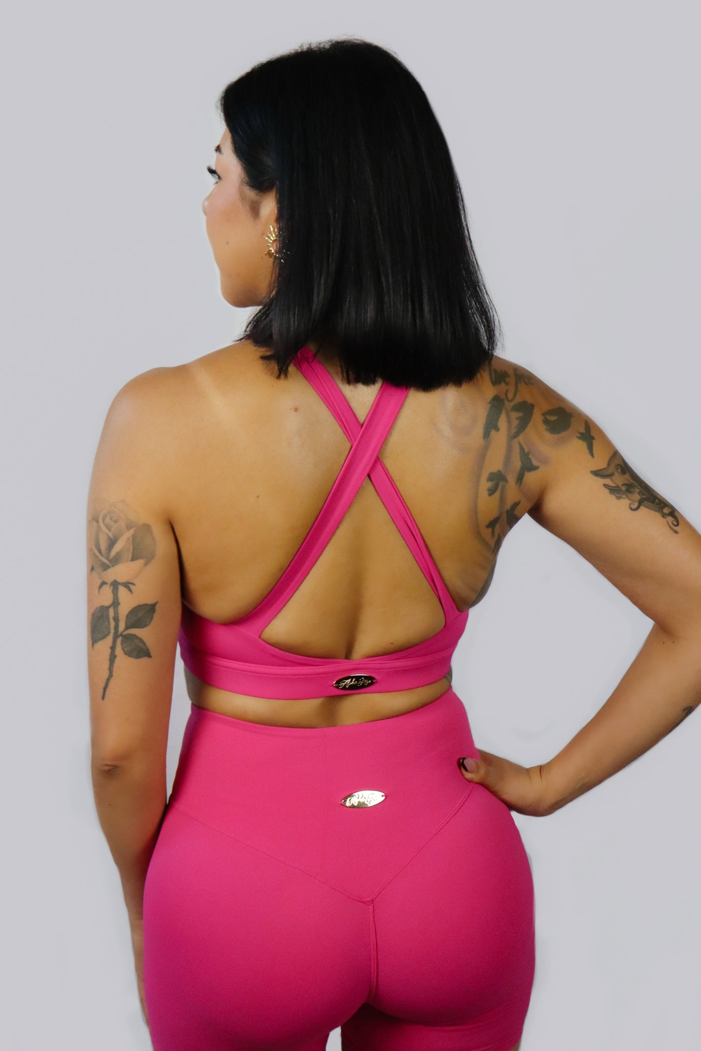 Person wearing a pink sports outfit with criss-cross back design on a gray background