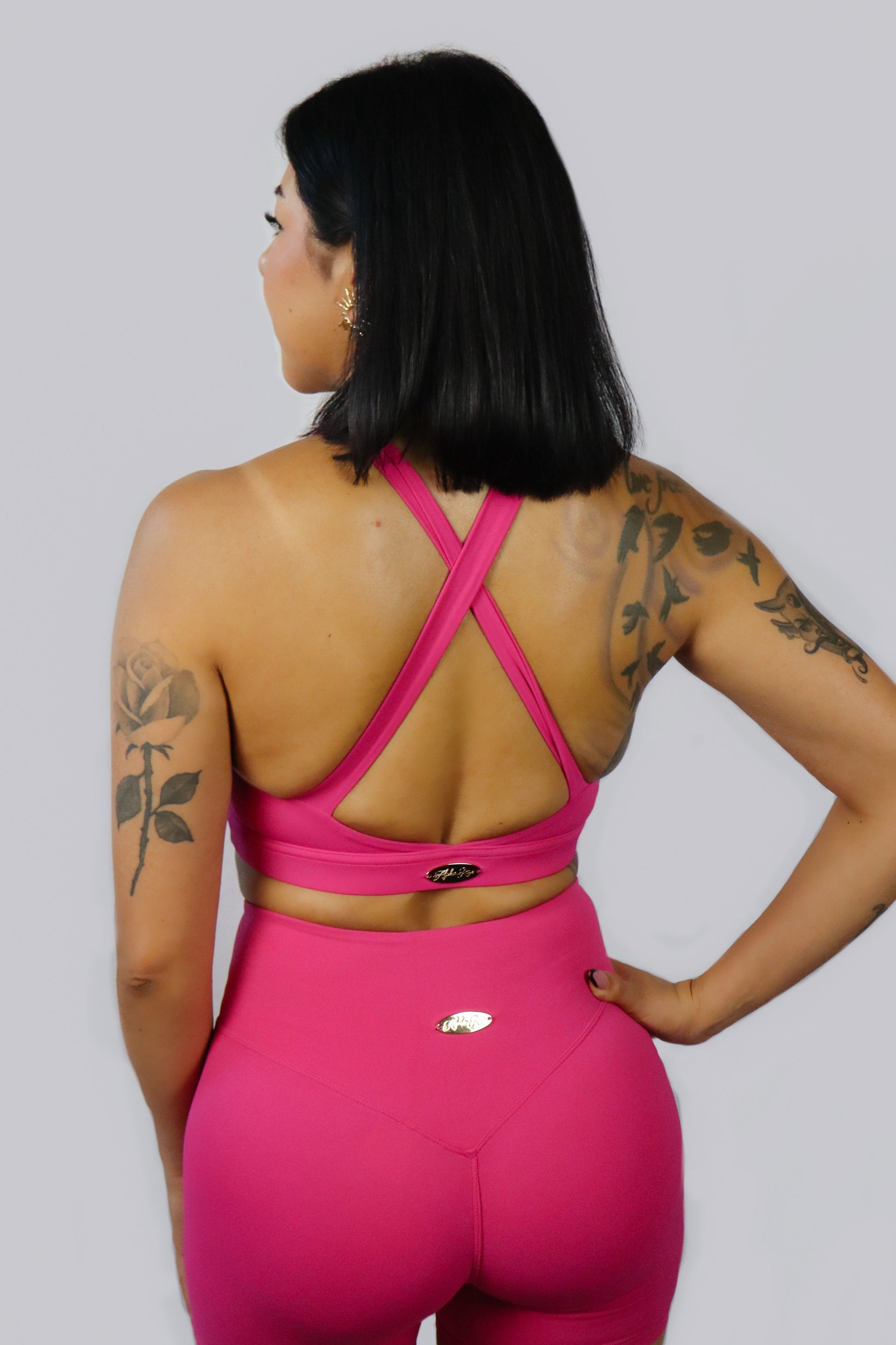 Person wearing a pink sports outfit with criss-cross back design on a gray background