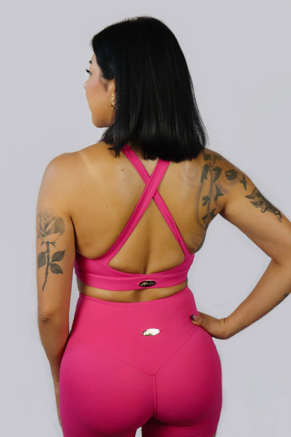 Person wearing a pink sports outfit with criss-cross back design on a gray background