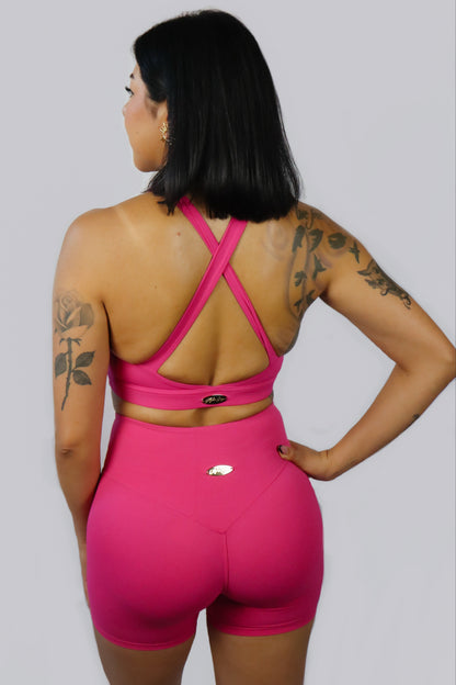 Person wearing a pink sports outfit with criss-cross back design on a gray background
