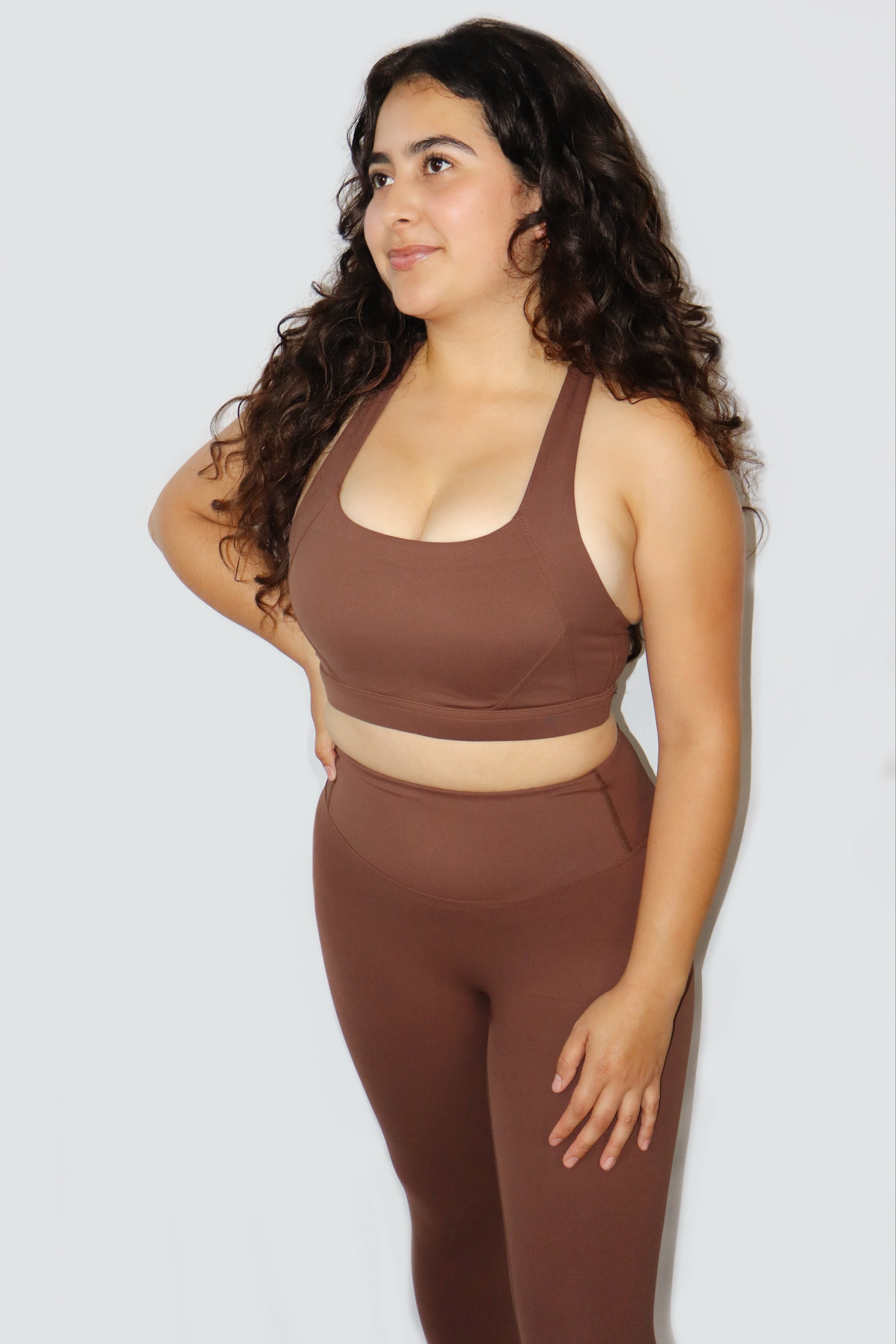 Woman wearing a brown sports bra and leggings set against a white background