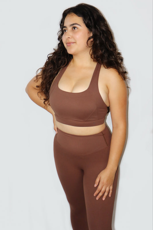 Woman wearing a brown sports bra and leggings set against a white background