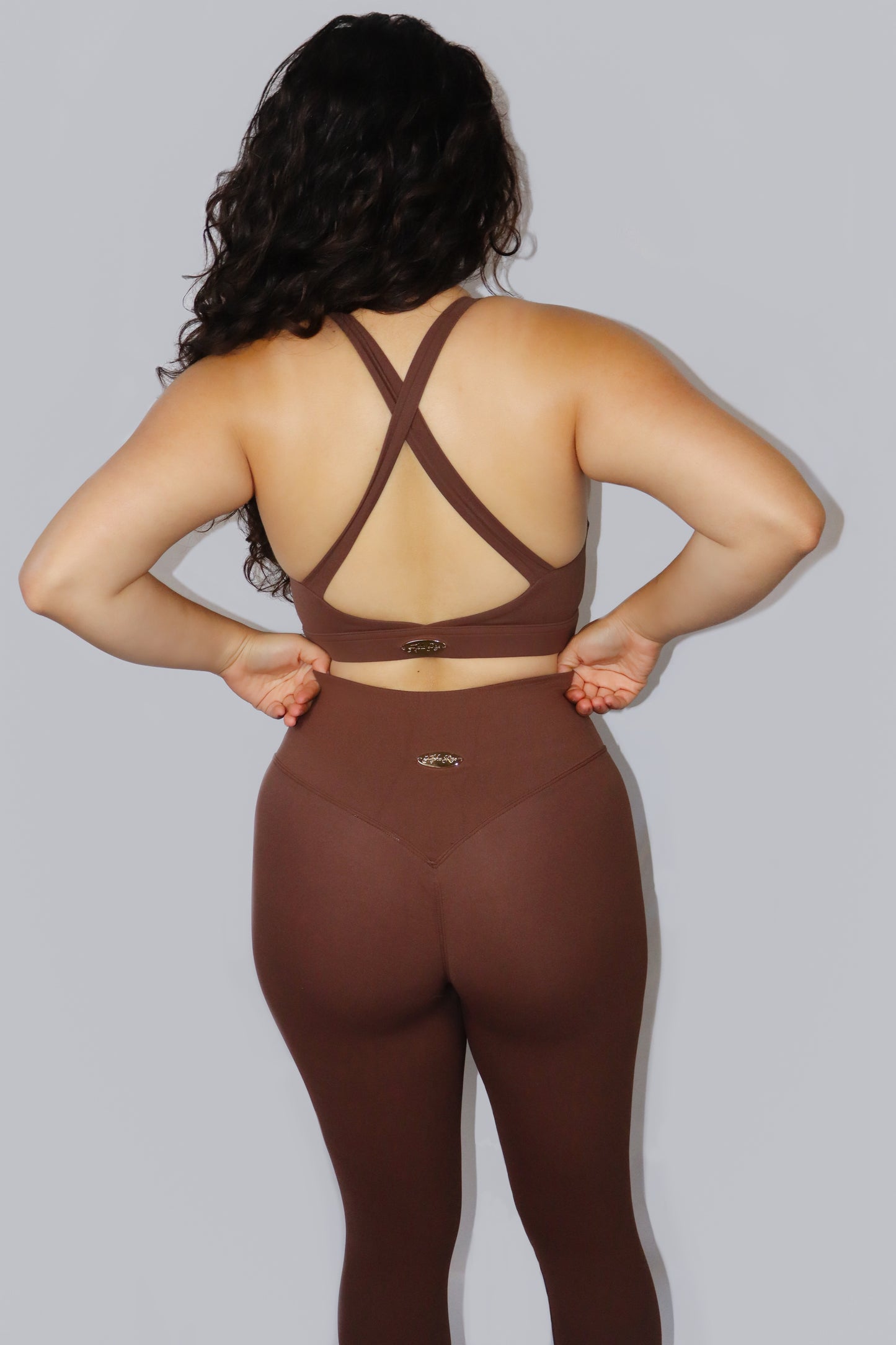 Person wearing a brown sports bra and leggings set on a plain background