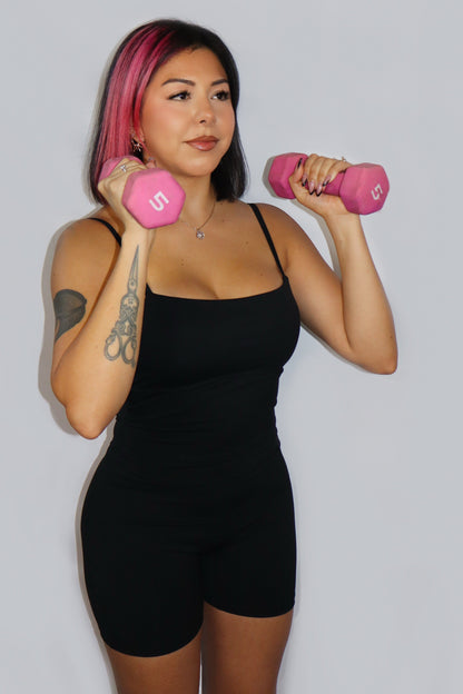 Woman holding pink dumbbells against a plain background