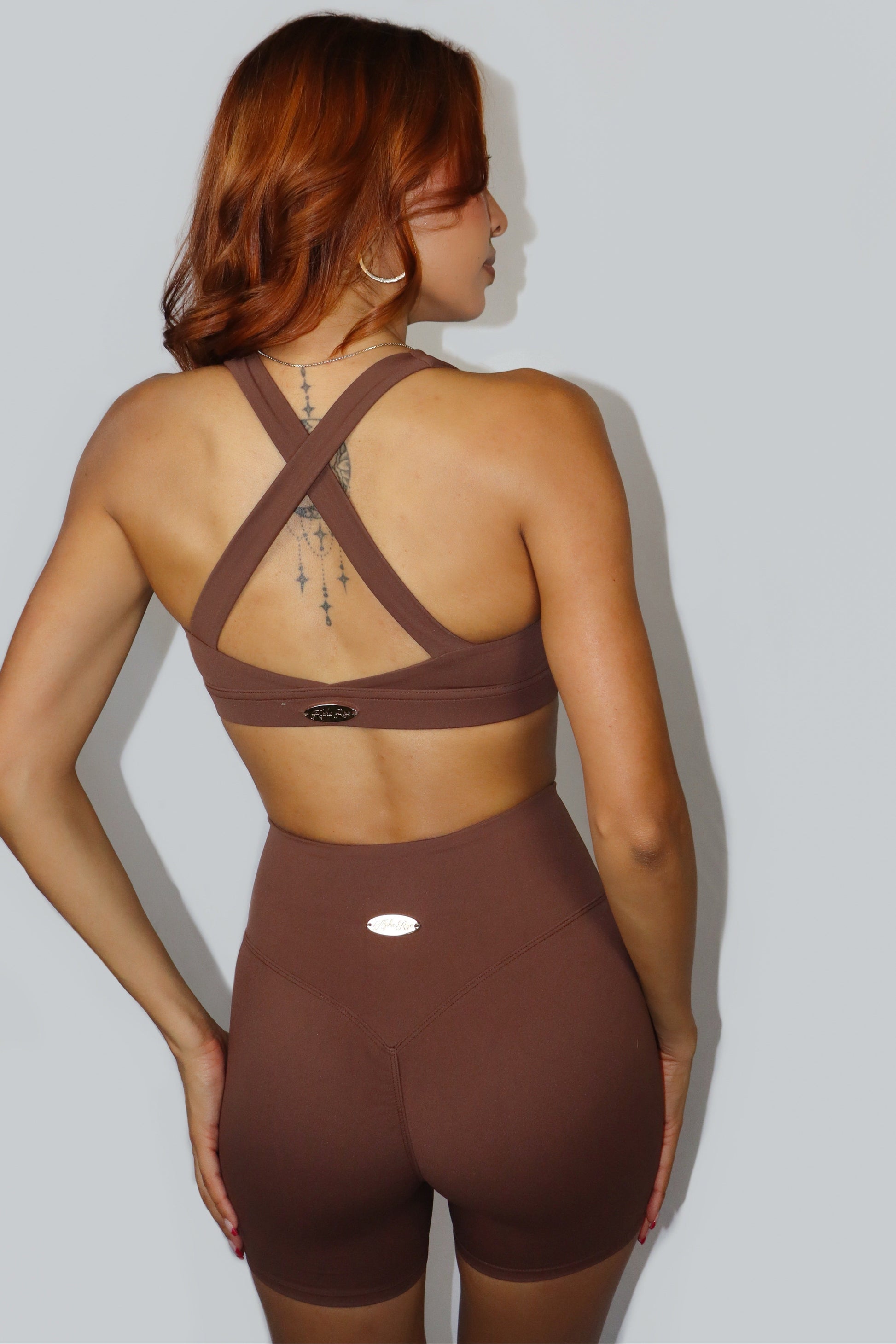 Person wearing a brown sports bra and shorts set on a light gray background